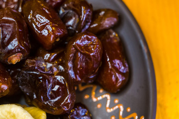 dried dates and figs in a ceramic plate on a wooden table