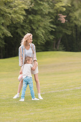 happy mother and daughter hugging and looking away in park