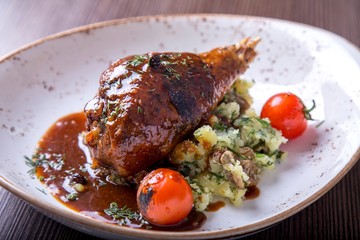 Tasty turkey leg in sauce with pounded mashed potatoes and tomatoes on a plate