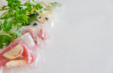 Fillet and vagatables in vacuum bags for sous vide coocing on white marbleized background