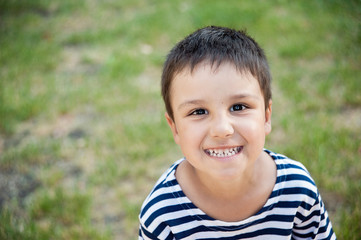 smiling boy in a vest looks at the frame