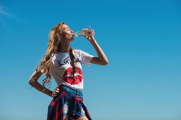 Young beautiful girl drinking water from a bottle in summer