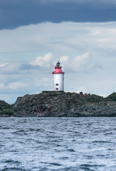 Scandinavian coastal landscape with lighthouse in dramatic lights