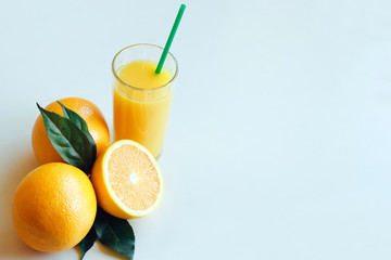 Glasses with orange juice next to orange slices with leaves on a white background. with space for text.
