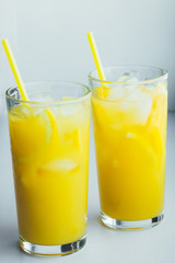 Naklejka na ściany i meble Glasses of orange juice with ice on a white background.