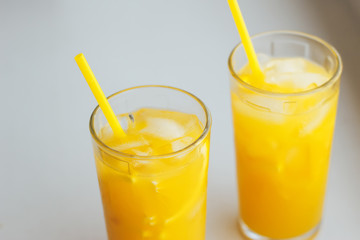 Glasses of orange juice with ice on a white background.
