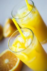 Glasses of fresh orange juice with ice and orange slices on a white background.