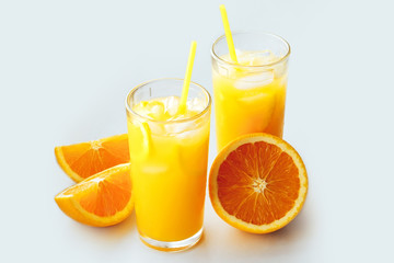 Glasses of fresh orange juice with ice and orange slices on a white background.