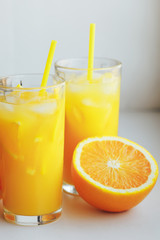 Glasses of fresh orange juice with ice and orange slices on a white background.