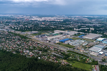 Fototapeta na wymiar Aerial view of wheat fields, meadow, forest andindustrial warehouses in rural Russia.