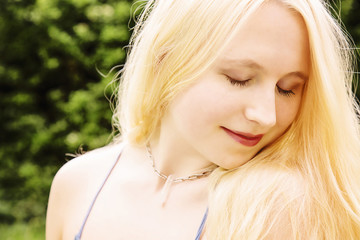 Naklejka premium Portrait of beautiful young woman with blond hair, blue eyes, and crystal quartz necklace