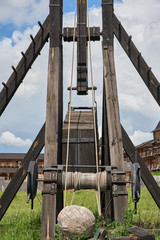 Fragment of an ancient wooden catapult against the background of fortress walls
