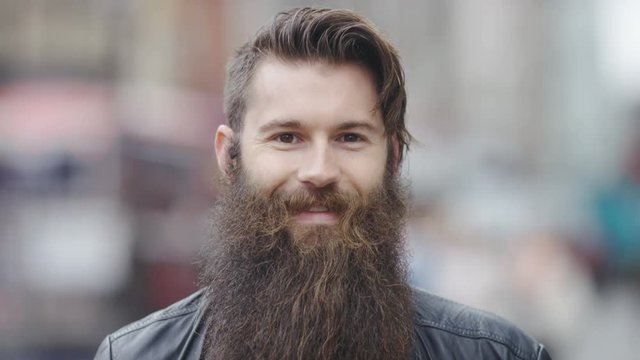 Close portrait of man with a long beard smiling to camera, in slow motion