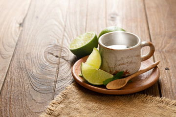 Cup of Warm Hot Lemon Drink with lemon slice on wooden background