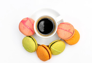 Cup of coffee on saucer with colorful macaroons on white background.. Top view.
