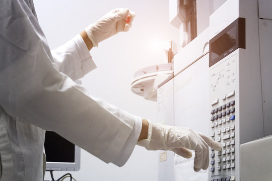 scientist holds an amber vial and press the control button of GC chromatography