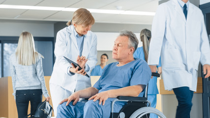 In the Hospital Female Doctor Shows Tablet Computer to Elderly Patient, Explaining his Condition. Modern Hospital with Best Possible Care.