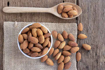 Almonds in a bowl and spoon on the wood table. Almonds are rich in nutrients,