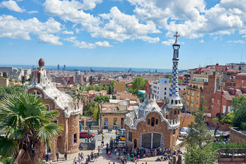 Barcelona, Spain. April 19, 2017: View of the entrance of Park Guell, the work of the architect Gaudi full of tourists with the guard house and the bookshop and panoramic view of Barcelona behind