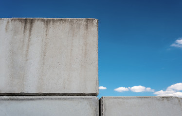 Fototapeta na wymiar Detailed background of concrete wall photo texture on blue beautiful sky background with white clouds.