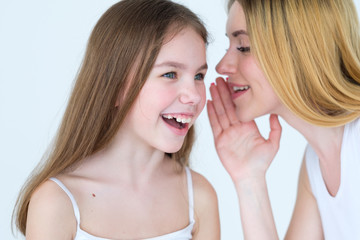 mom and kid communication. mother sharing a secret. woman whispering something into her daughter ear.