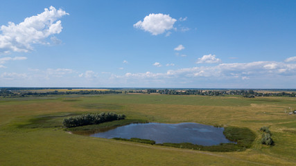 Naklejka premium Aerial view of a small pond parallel to a country road in Saxony-Anhalt with fields and forests in the surrounding area, made with drone