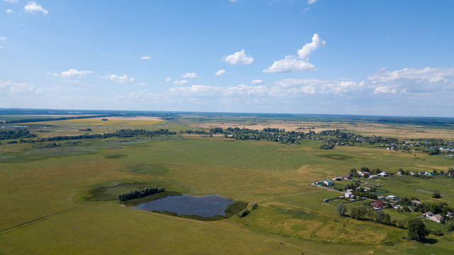 Aerial view of a small pond parallel to a country road in Saxony-Anhalt with fields and forests in the surrounding area, made with drone
