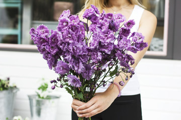 Bouquet of purple lilac delphinium in women's hands on the street