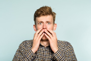 scared shocked terrified frightened startled man clutching hands to his face. portrait of a young...