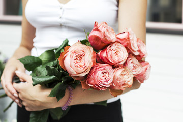 Young woman florist holding bouquet of pink roses at the street