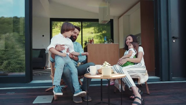 Little cute boy sits on his father&rsquo;s knees, happy family having breakfast outside the house on fresh air. Cuteness, being happy together, joy of life. Family portrait