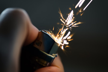Lighters with flame sparking on dark background. Selective focus and shallow depth of field. - obrazy, fototapety, plakaty
