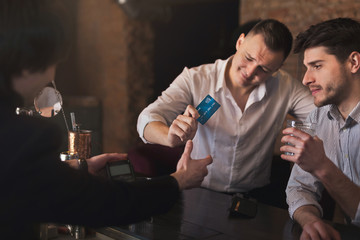 Drunk man paying via credit card in bar