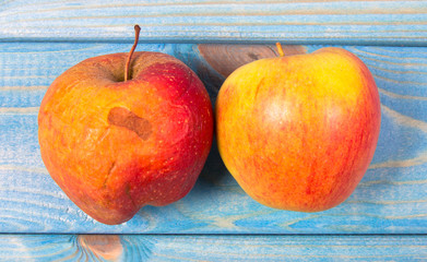 Wrinkled, rotten apple on blue background. Close Up.