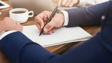 Male hand holding pen ready to make note in opened notebook