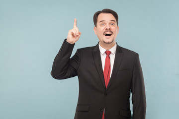 Finally I realized the solution! An ingenious idea came and it is clear what to do next. studio shot. isolated on blue background. businessman with black suit, red tie and mustache looking at camera