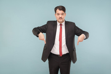 Now that you look down. indoor studio shot. isolated on light blue background. handsome businessman with black suit, red tie and mustache looking at camera.