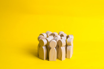 Group of wooden people figurines on a yellow background. Crowd, meeting, social activity. Society,...