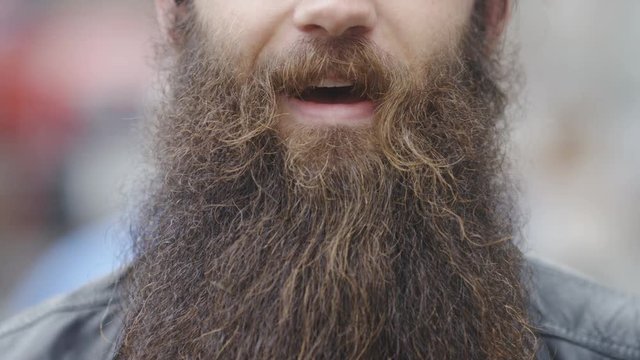 Close up of a man's mouth with a bushy big beard talking to camera