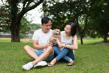 Lovely asian couple with their pet shih tzu puppy at outdoor park
