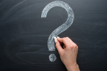 Question mark, drawn chalk on a blackboard with a girl's hand