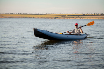 A young man is riding a kayak. Quiet waters and bright sun.