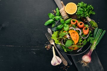 Naklejka na ściany i meble Fresh Vegetable Salad. Arugula, tomatoes, carrots, onions. On a wooden background. Top view. Copy space.