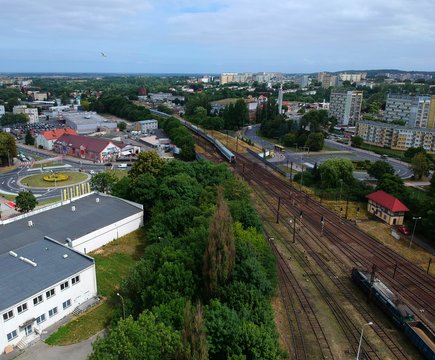 Cargo and passenger wagons on train station in city, aerial view, road roundabout intersection with bridge