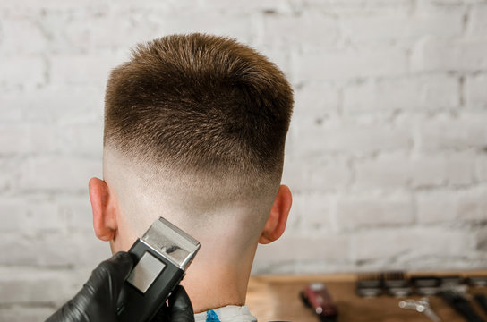 Barber does hair cut of nape young guy on a brick wall background. Back  view. Stock Photo | Adobe Stock
