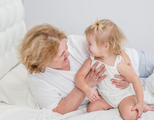 Obraz na płótnie Canvas Grandmother and baby girl having fun on the bed