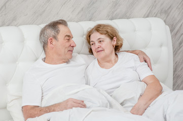 Happy elderly couple together on the bed
