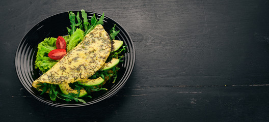 Omelet with vegetables and avocados. Fried eggs. On a wooden background. Top view. Free copy space.