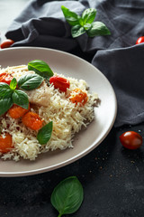 Steamed cod fish with rice and cherry mix tomatoes and basil herbs in a plate