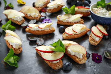 Healthy breakfast toasts with cottage cheese and nectarine slices, sprinkled with cinnamon, served with dark grapes and edible flowers